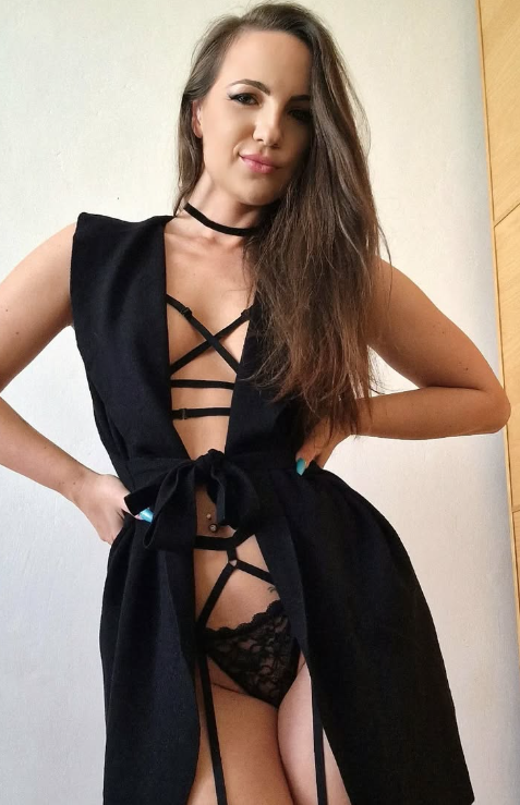 Kristy Black se fotí v sexy černé bundě a černých kalhotkách s rukama v pase.