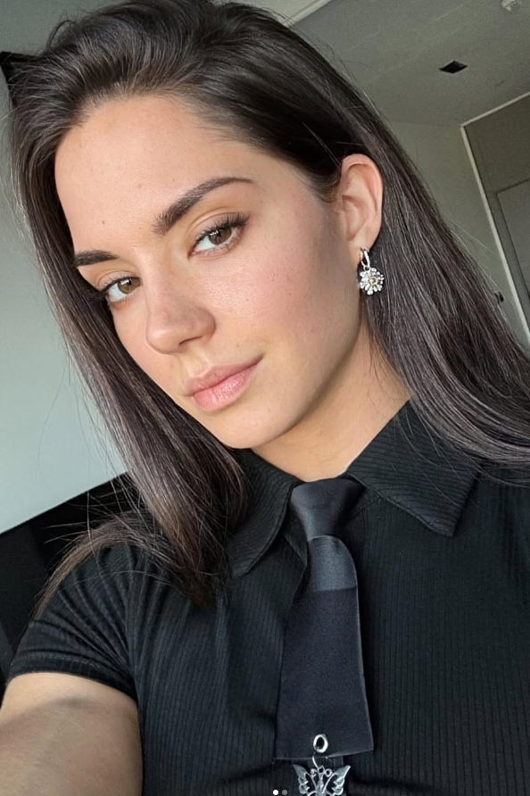 Vladislava Galagan si pořizuje selfie v černé košili s límečkem a černé kravatě.