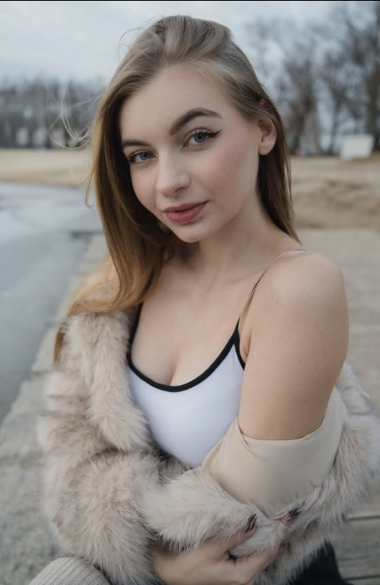 Kortie se fotí venku oblečená v sexy bílém topu, černých kraťasech a bílé kožešinové bundě.