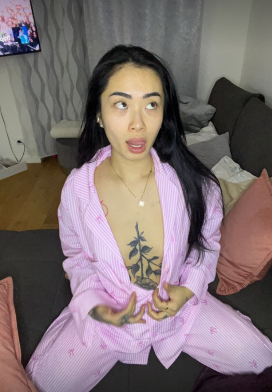Asia Nina se fotí, když klečí na gauči a je oblečená v sexy růžovém pyžamu