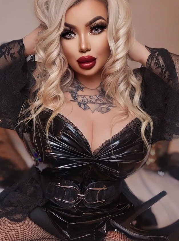 Rebecca Randallová se fotí v sexy černých šatech s rukama na hlavě.