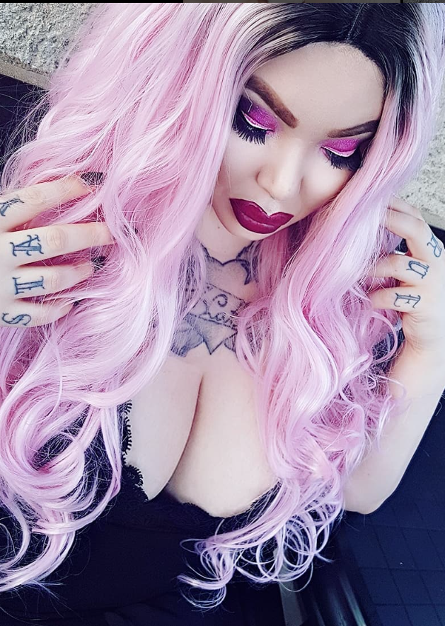 Rebecca Randall taking a picture while wearing a sexy black outfit with her hand on her shoulders