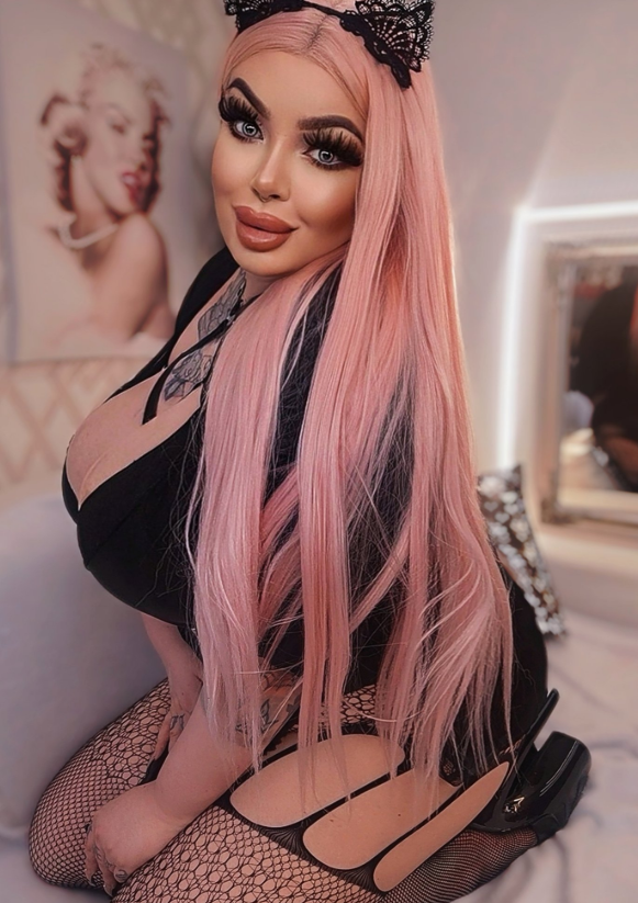 Rebecca Randallová se fotí, zatímco klečí na podlaze, oblečená v sexy černých šatech a s kočičíma ušima.
