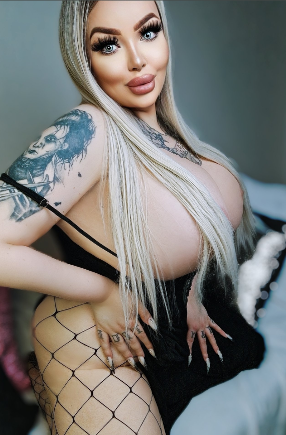Rebecca Randallová se fotí na posteli a oblečená v sexy černých šatech.