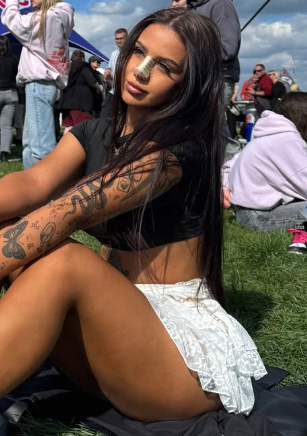 Petulka v černém topu a bílé minisukni sedí na trávě