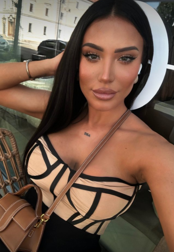 Natali Fuentess oblečená v sexy hnědých šatech a bílém klobouku.