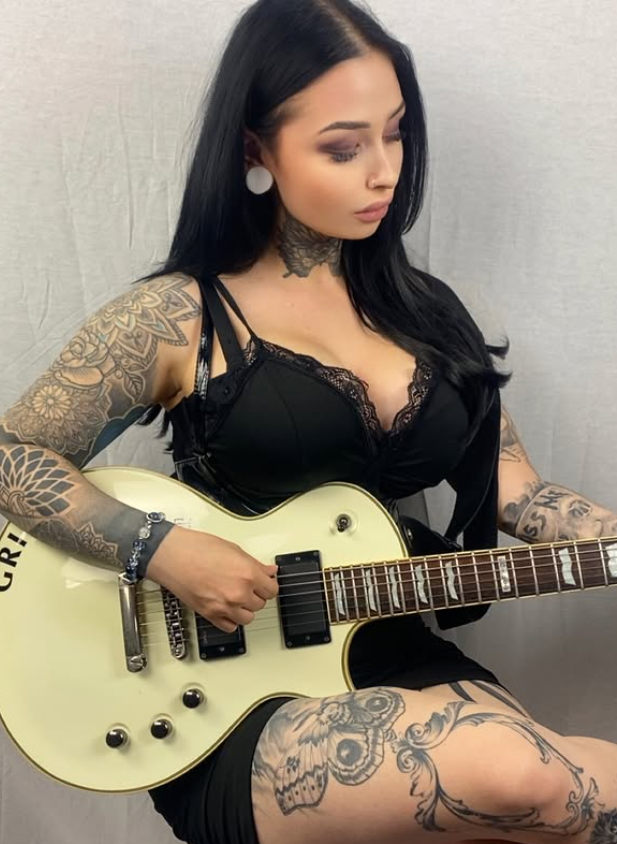 Tereza Šimánová oblečená v sexy černém topu a s kytarou v ruce