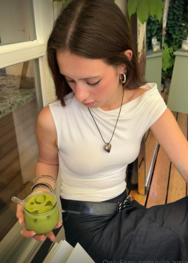 Amalka Amalie má na sobě sexy bílý top a černé kalhoty, zatímco v rukou drží drink